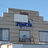 Pixelated static image of a building facade with multiple windows and a blue sky background.