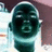 Pixelated static image of a stylized human face with dark green skin, white eyes, and a light blue collar against a blurred background.