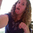 Woman with long brown hair in dark sleeveless top, fist raised near chest, mouth open in mid-expression, visible in four