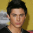 Pixelated close-up of a person with dark hair against a yellow background, wearing a black top.