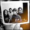 A black-and-white photograph of four people holding a framed photo with Arabic text, held by a hand in the foreground.