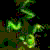 Pixelated green and brown abstract shape with scattered dark red, blue, and purple accents on a black background.