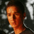 A pixelated image of a person with short dark hair wearing a dark shirt, positioned next to green text on a black background.