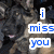Pixelated image with blue text reading 'i miss you' on white rectangular backgrounds against a dark, blurry grayscale backdrop.