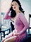 Pixelated static image of a woman in a pink dress with dark hair and red lipstick posing against an outdoor background.