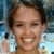 Pixelated static image of a person with light skin tone, dark hair, closed eyes, and a broad smile showing teeth against a blurred background.