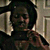 Pixelated static image of a person with dark hair and light skin, wearing a white shirt against a muted background.