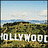 Pixelated landscape with blue sky, clouds, and green-brown terrain featuring white text reading "HOLLYWOOD" in block letters.