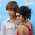 Two people in formal attire pose together, one in a white shirt and the other in a red dress against blue background.