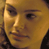 Pixelated close-up of a human face with warm yellow-brown tones and visible dithering, showing partial facial features including eyes, nose, and mouth against a dark background.