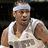 Pixelated image of a person wearing a white headband and white sleeveless jersey with orange and blue accents, set against a dark background.