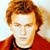 Static pixelated image of a person with reddish-brown hair wearing a red top against a light background.