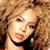 Animated contact sheet showing two frames of a celebrity with curly hair and a blue background containing text, arranged in a 2x2 grid layout.