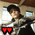 A person in a dark cap and gray jacket holds two heart symbols that change color across six