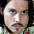 Pixelated close-up of a person's face with light skin, dark hair, blue eyes, and a mustache, wearing a dark jacket over a light shirt.