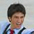 A pixelated image shows a person with short dark hair wearing a white shirt, red tie, and dark suspenders against a light background. To the right is green text reading "Evan Lysacek" on a solid green field.