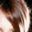 Three smiling people with light brown hair against a dark background, one person partially visible on the right.