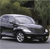 Pixelated image of a silver sedan with black trim parked on a street, background shows blurred green foliage and dark shapes.