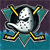Pixelated icon of a white narwhal with black spots, yellow tusk, and teal fins against a dark purple and blue background.