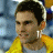 Pixelated static image of a person with short dark hair wearing a yellow garment against a blurred blue and orange background.
