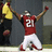 A pixelated image of a football player in red jersey with number 21, white pants, and red shoes celebrating on a field, surrounded by text overlays.
