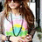 A pixelated image of a person with long brown hair wearing a white top and colorful layered shorts in pink, yellow, green, and blue.