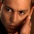 A pixelated close-up of a person's face with a hand resting near the cheek, rendered in warm brown and orange tones.