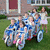 Group of people on a bicycle cart with text overlays listing names and 'John and Kate plus 8!!' against a house background.