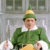 Two identical figures in green elf costumes with white collars and yellow hats sit side-by-side against a gray building background, red text reads 'papa elf' between them.