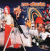 Animated sequence shows two distinct scenes: a group with red-haired figures in white and orange against dark background, then three people in black tops and pink pants on plain backdrop.