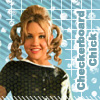 A pixelated image of a person with blonde curly pigtails wearing a black and white patterned top against a blue grid background with white cloud shapes.