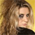 A pixelated close-up of a person with long wavy brown hair, wearing a black top against a yellow background.