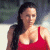 A woman with long dark hair in a red sleeveless top stands against a blurred background, next to green text reading 'Original Icons .com' on a solid green backdrop.