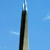 Tall, narrow vertical object with dark central section and light gradient edges against blue sky background.