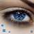 A close-up of a blue eye with pixelated iris details, surrounded by light skin tones and brown eyebrows, featuring scattered blue squares on the left side.