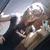 Pixelated image of a person with light hair holding a dark object against a blurred background with light and dark tones.