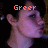 Pixelated image of a person's face with a raised hand, overlaid with red text reading 'Greer' against a dark background.