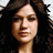 Pixelated close-up of a person with dark curly hair against a light background, showing facial features and neck.