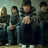 Pixelated image of four people in dark clothing on left, bright cyan background with white pixelated text and heart symbols on right.