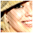 Pixelated close-up of a person's face with visible eye, nose, mouth, and hair details in warm tones.