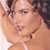 Pixelated close-up of a person with light skin tone, brown curly hair, and a white strap visible on the shoulder.