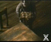 Animated scene of a figure in dark clothing holding a golden object on a wooden structure with railings, viewed from above.