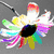 Colorful flower with rainbow petals and black center, grayscale chain-link necklace, abstract brown background with green lines, blue eye with rainbow eyeliner.
