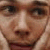 Pixelated close-up of a person's face showing eyes, nose, and mouth with light brown hair visible on the right side.