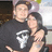 Two people embrace in a dark room with balloons; the person on the left wears a black shirt with white graphic design.