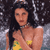 Static pixelated image of a person with long dark hair wearing a yellow bikini top, set against a blurred background with light and dark tones.