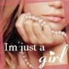 A close-up of a person with light brown hair holding a hand near their face, wearing a necklace and rings, with text overlay reading "I'm just a girl".