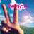 A hand making a peace sign against a blue sky with clouds and green hills, with pink text reading 'peace' or '=]' above it.
