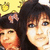 Two people with dark hair pose closely together against a yellow background with pixelated shapes.