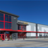 Pixelated static image of a building with red structural elements against a blue sky background.